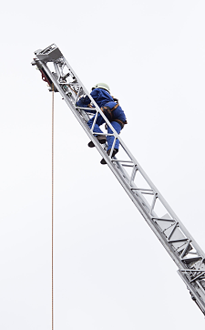 Eine Person steigt beim Einstellungstest die ausgefahrene Feuerwehr-Drehleiter hoch