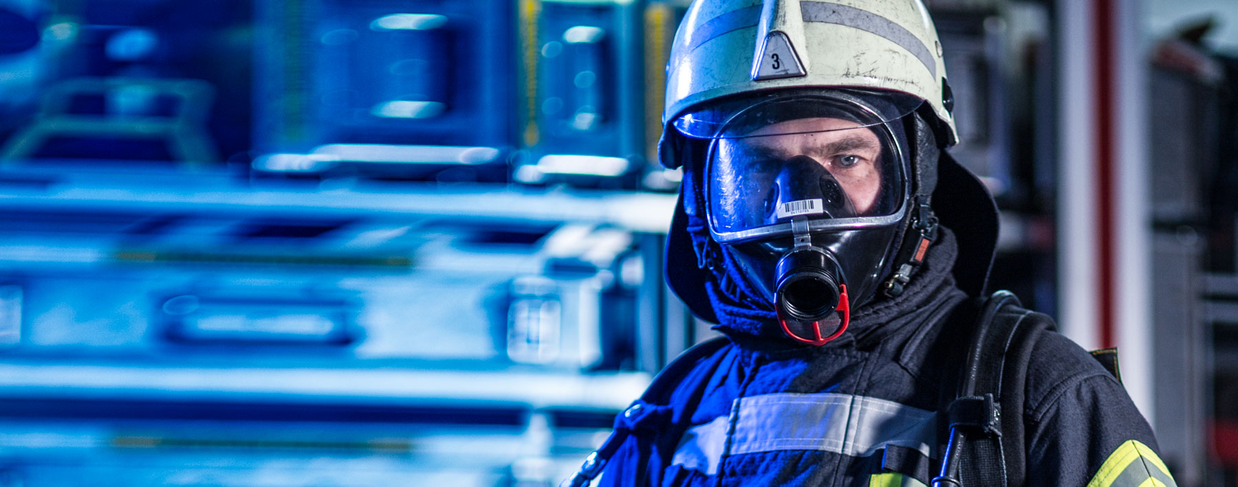 Feuerwehrmann mit Atemschutzmaske vor unscharfem Hintergrund
