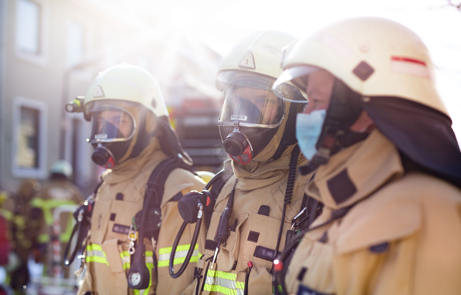 Drei Feuerwehrmänner in Bereitstellung mit Atemschutzmaske