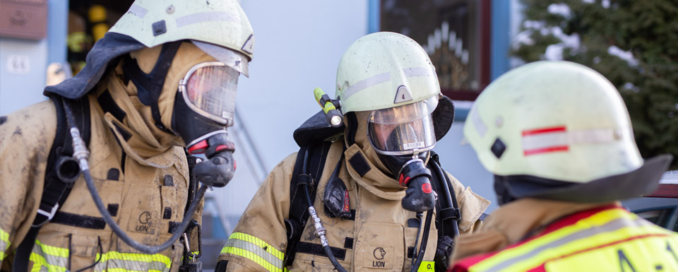 Zwei Atemschutz-Geräteträger sprechen mit einem Einsatzleiter