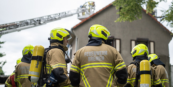 Einsatzkräfte der Feuerwehr Bremen von hinten fotografiert, mit Blickrichtung zu einer Brandwohnung