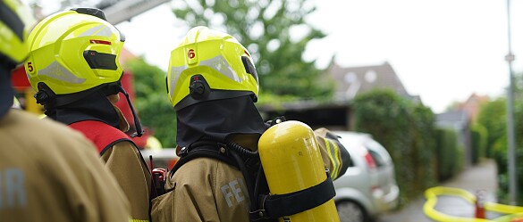 Zwei Einsatzkräfte der Feuerwehr Bremen, von hinten, mit Bild zu einem Brandobjekt.