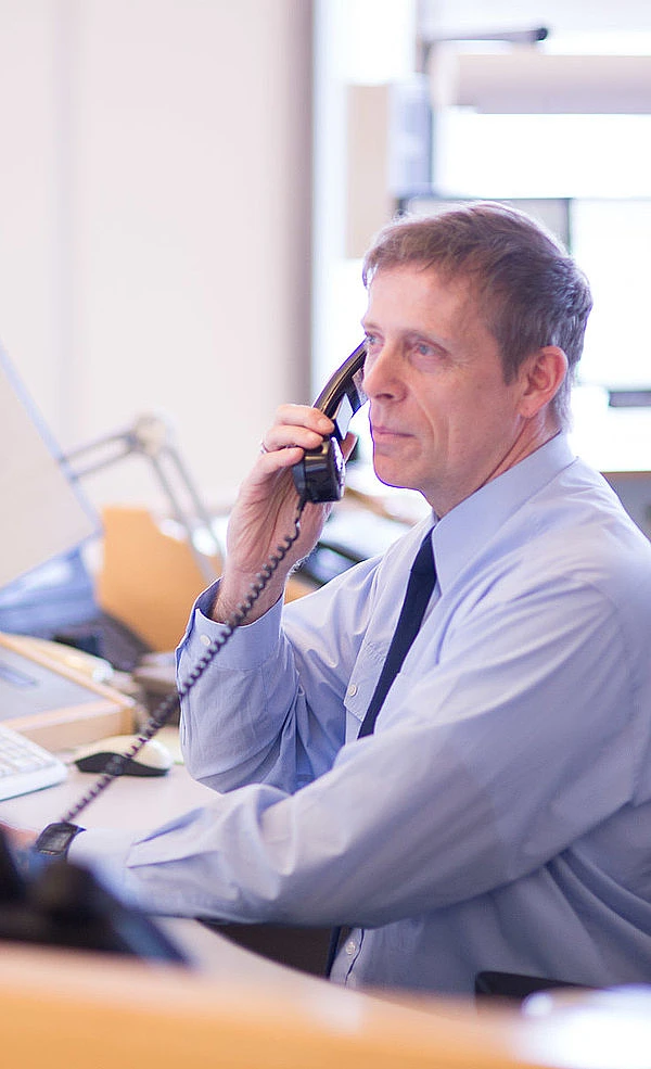 Ein Disponent in der Feuerwehr- und Rettungsleitstelle mit Telefonhörer am Ohr.