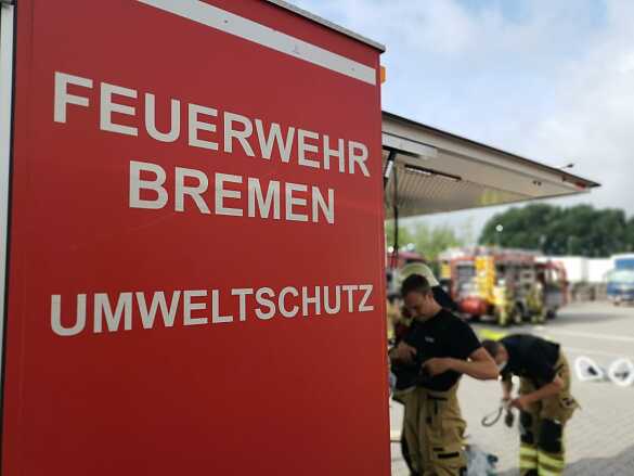 Ein Symbolbild des Abrollbehälters Umweltschutz im Einsatz, mit unscharfer Einsatzszene im Hintergrund