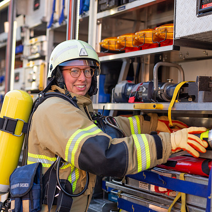 Eine Feuerwehrfrau mit Atemschutzgerät neben einem Löschfahrzeug