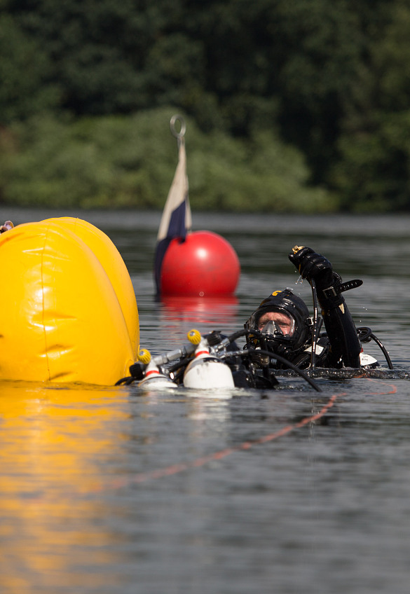 Ein Feuerwehrtaucher im Wasser bei einer Übung mit einem gelben Hebesack